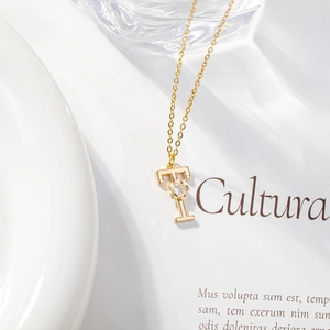 Macro detail of gold letter pendant with micro-set zircon on white aesthetic background