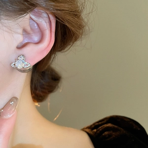 Close-up of silver Saturn stud earrings with zircon and pearl on female model