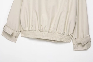 Detail of waterproof trench coat showing elastic hem and adjustable cuffs in beige