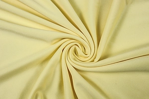 Detail of soft pale yellow knitted fabric with elegant drapes and smooth texture