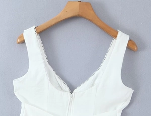 Détail d'un haut blanc à col en V avec bordure en dentelle et fermeture éclair invisible