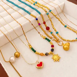 Parure de colliers plaqué or avec pendentifs gourde et cœur sur un plateau à bijoux