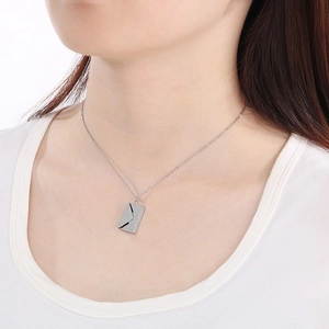 Gros plan d'un collier pendentif enveloppe argentée sur modèle au fini poli brillant