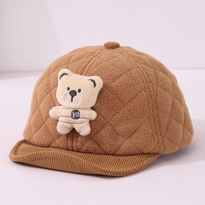Detail of warm brown baby cap with diamond quilting, plush bear, and corduroy brim