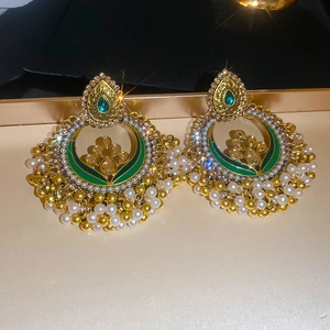 Detail of ethnic crescent earrings with green enamel and white pearl tassels