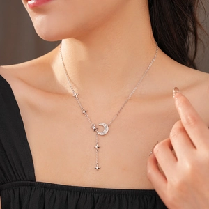 Detail of silver Y-shaped necklace with zircon moon and star pendants worn by model