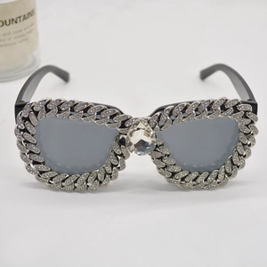 Macro detail of cat-eye sunglasses with rhinestone Cuban chain and large crystal centerpiece