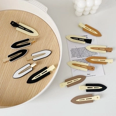 Close-up of floral hair claws in neutral colors displayed on a wooden tray and white desk