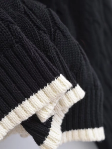 Detail of cable knit pattern and contrast white ribbed cuffs on a black cardigan