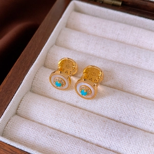 Detailed close-up of vintage gold earrings with turquoise, mother of pearl and zircons
