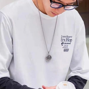 Detailed close-up of a silver headphone pendant necklace worn by a male model