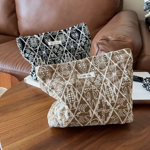 Detailed embroidery texture on linen makeup bags with leaf and fish patterns