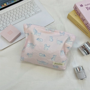 Pink floral cotton makeup bag with cat prints shown with lifestyle travel accessories