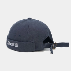 Detail of navy blue docker hat with white Brooklyn embroidery and adjustable strap