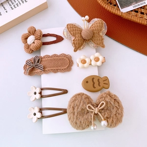 Dettaglio del set di 7 fermagli per capelli in peluche marrone con fiocchi e fiori