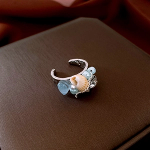 Detailed view of silver Bohemian shell and pearl ocean style ring on jewelry box