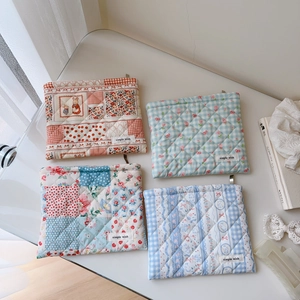 Vue à plat de quatre pochettes en coton matelassé aux motifs floraux et à carreaux variés