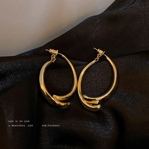 Elegant gold twisted hoop earrings with minimalist design on black silk background