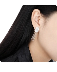 Close-up of irregular silver tassel earrings with textured geometric design on model
