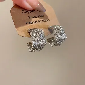 Minimalist silver-colored pleated C-shaped hoop earrings with a textured metal finish