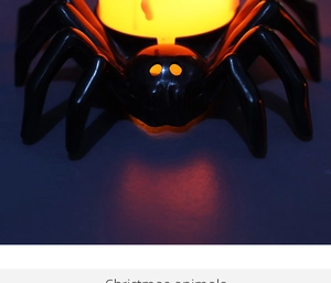 Close-up of a black Halloween spider lamp with glowing warm yellow LED light and detailed eyes