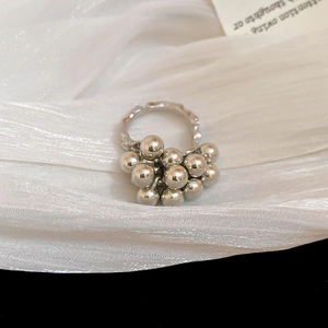 Detailed macro of silver cluster ball ring on soft white silk background texture