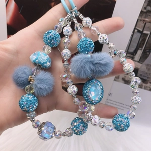 Detail of blue beaded phone strap with fuzzy pom-poms and crystal charms