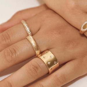 Stackable 18K gold-plated textured and star-engraved rings set on model's hand