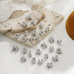 Detailed view of silver letter charms A-Z and heart with cubic zirconia inlay on stone