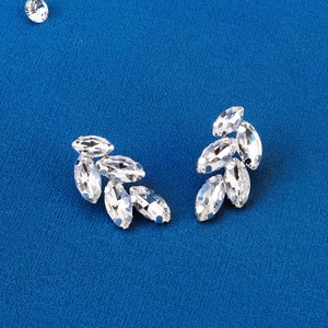 Close-up of elegant leaf-shaped crystal hair clips on a dark blue textured background