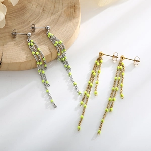 Detailed view of long tassel earrings with metallic chains and bright yellow resin beads