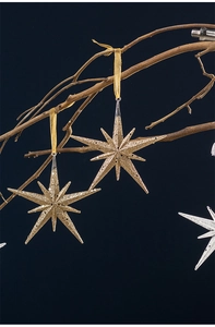 Detail of glittery star Christmas ornaments in gold and silver on tree branches