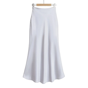 Détail d'une jupe longue en satin blanc taille haute avec texture soyeuse et drapé fluide
