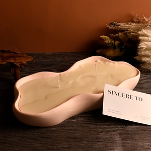 Détail du bougeoir en céramique rose ondulée avec deux mèches et cire de soja blanche