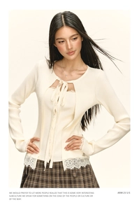 Détail d'un cardigan en maille crème avec dentelle et nœud sur une jupe écossaise