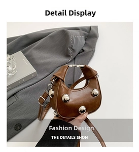 Detail of a brown leather mini dumpling bag with large silver stud accents and metallic lock