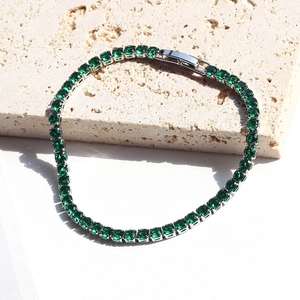 Detailed macro of a silver tennis bracelet featuring vibrant square emerald green zircons
