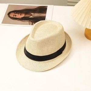 Classic straw fedora hat with black ribbon band on white table in a lifestyle setting
