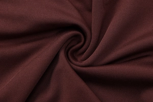 Macro texture of deep burgundy ribbed knit fabric showing soft elasticity and fine detail
