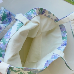 Gros plan de l'intérieur d'un sac cabas en coton avec poche ouverte et motifs floraux
