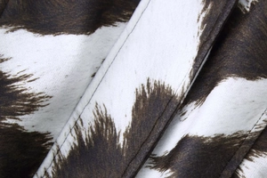 Close-up of soft cow print fabric with brown and white spots and fine stitching detail