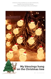 Close-up of LED snowman string lights with red hats on a snow-covered Christmas tree