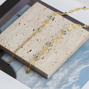 Detail view of gold Evil Eye necklace with blue resin beads and butterfly link accents