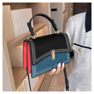 Détail du sac à main tricolore avec rabat noir, base bleue et côtés rouges contrastés