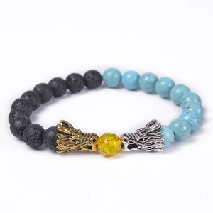 Detailed close-up of natural lava stone bracelet with golden and silver dragon heads