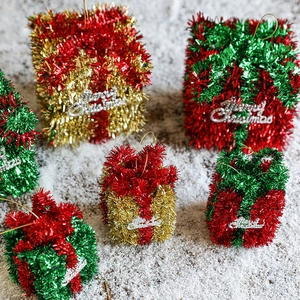 Glittery Christmas gift box ornaments in red, gold, and green on a snowy background