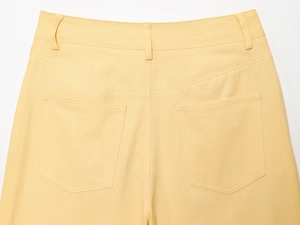 Détail du pantalon jaune en coton montrant les poches arrière et les coutures de la taille