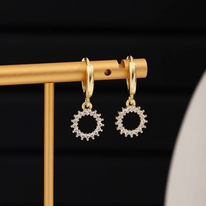 Detail of gold hoop earrings with sparkling hollow round pendants on a metal display stand