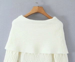 Detailed close-up of white knit off-shoulder dress texture on a wooden hanger