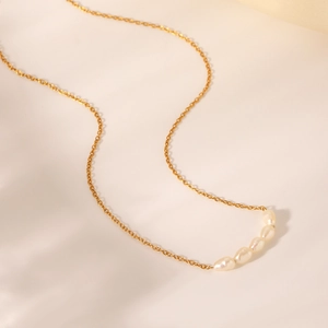 Detailed close-up of five oval freshwater pearls on an 18K gold plated necklace chain